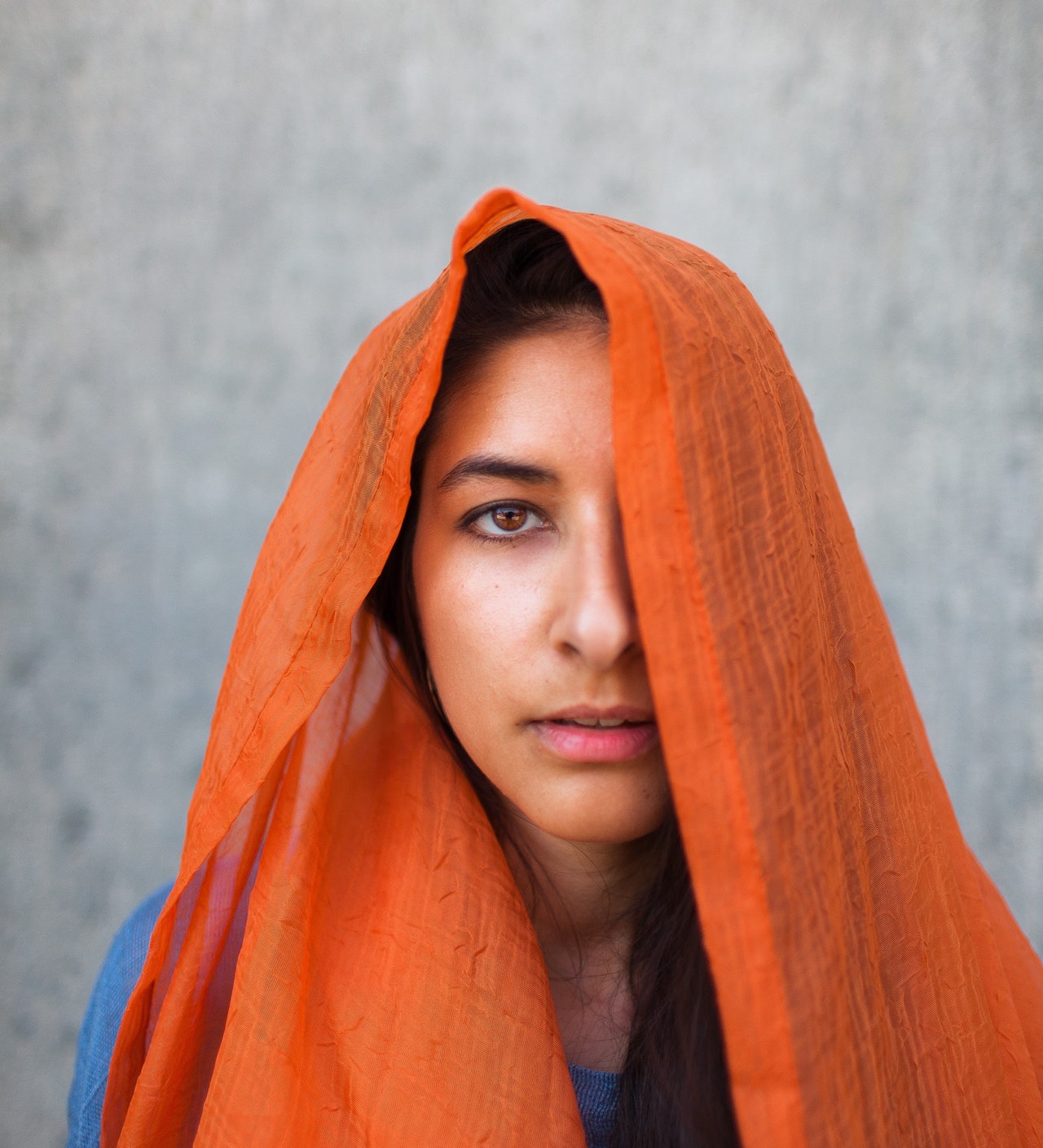 woman-covering-head-with-orange-scarf-3212784